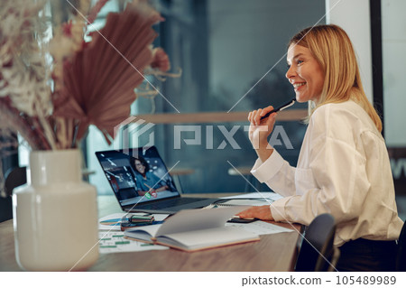 Smiling businesswoman talking with client via videocall while sitting in modern coworking space Smiling businesswoman talking with client via videocall while sitting in modern coworking space 105489989