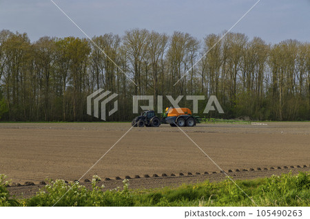 Tractor with sprayer during spring work on the field 105490263