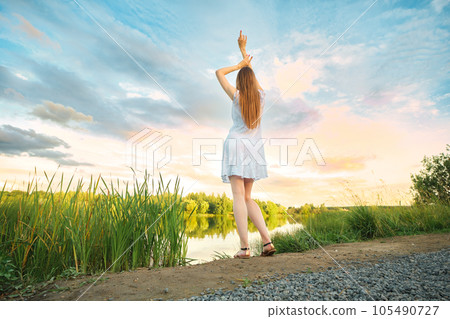 Woman looking at sunset standing by the river 105490727