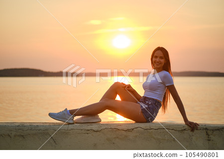 Smiling woman on a pier at sunset Smiling woman on a pier at sunset 105490801