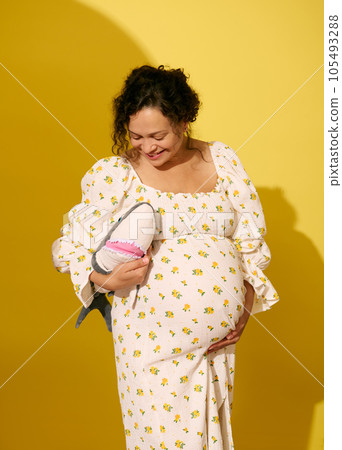 Cheerful pregnant woman smiling, holding plush shark toy, isolated over yellow studio background Cheerful pregnant woman smiling, holding plush shark toy, isolated over yellow studio background 105493288