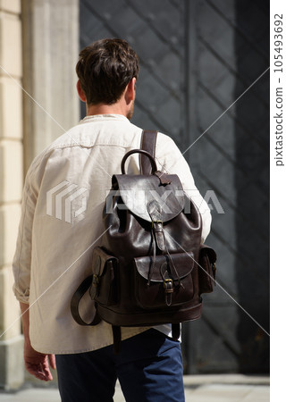 Handsome businessman walking on the street, with luxury leather dark brown backpack. Fashionable style. Handsome businessman walking on the street, with luxury leather dark brown backpack. Fashionable style. 105493692