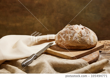 Homemade sourdough bread loaf with crispy crust and knife on wooden rustic board. 105494771