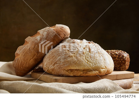 Assortment of baked bread on wooden table over brown studio background. Assortment of baked bread on wooden table over brown studio background. 105494774