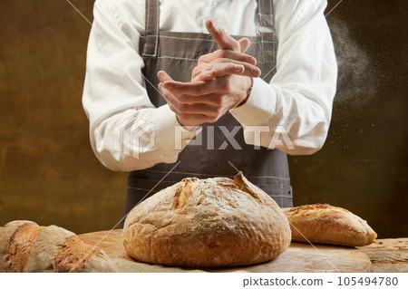 Baker cooking bread. Man slaps flour over the dough. Men's hands with flour clap. Baker cooking bread. Man slaps flour over the dough. Men's hands with flour clap. 105494780