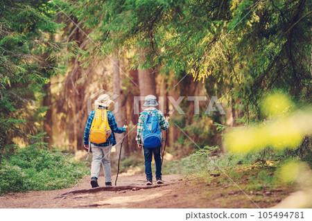 Two boys with backpacks hiking together in the wilderness forest. Two boys with backpacks hiking together in the wilderness forest. 105494781