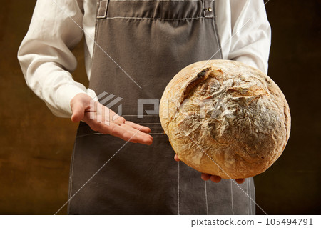 Baker holds freshly baked homemade sourdough bread. Baker holds freshly baked homemade sourdough bread. 105494791