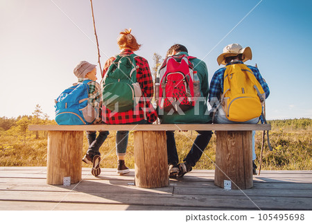 Mother and father with two sons sitting and relaxing on the bench after hiking. 105495698