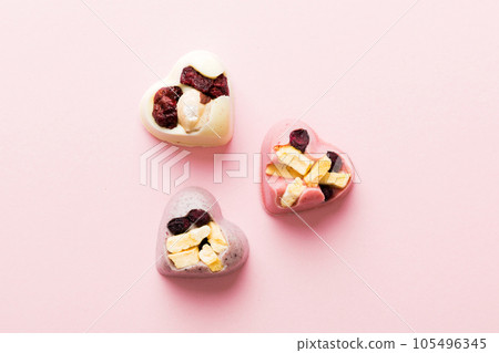 chocolate sweets in the form of a heart with fruits and nuts on a colored background. top view with space for text, holiday concept 105496345