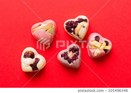chocolate sweets in the form of a heart with fruits and nuts on a colored background. top view with space for text, holiday concept 105496346