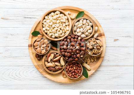 mixed nuts in wooden bowl. Mix of various nuts on colored background. pistachios, cashews, walnuts, hazelnuts, peanuts and brazil nuts mixed nuts in wooden bowl. Mix of various nuts on colored background. pistachios, cashews, walnuts, hazelnuts, peanuts and brazil nuts 105496791