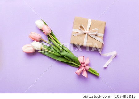 Pink tulips flowers and gift or present box on colored table background. Mothers Day, Birthday, Womens Day, celebration concept. Space for text top view 105496815