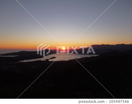 Aerial drone view of beautiful sunset or sunrise landscape with clear sky in the Bay of Kotor, Adriatic sea, Montenegro. Tranquil skyline with bright orange sunlight. Summer holiday concept 105497348