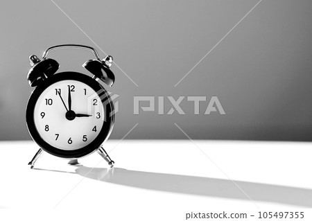 Modern black and white alarm clock in retro style isolated on white and grey background with shadow showing time three hours in afternoon. Siesta time, break, lunch concept. Modern black and white alarm clock in retro style isolated on white and grey background with shadow showing time three hours in afternoon. Siesta time, break, lunch concept. 105497355