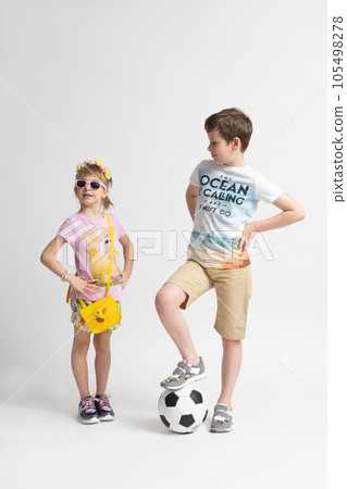 The older boy with the soccer ball looks at the younger girl appraisingly. 105498278