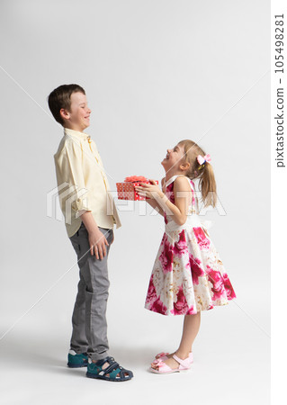 The younger girl gives a gift to the older boy - brother or friend. 105498281