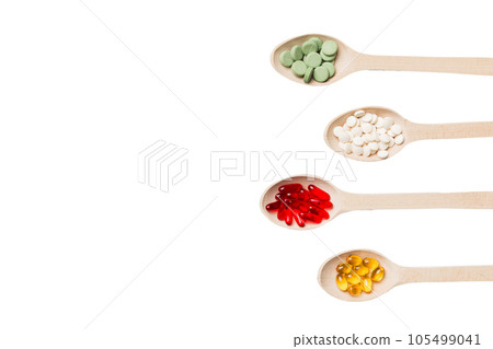 Top view Variety of vitamin and mineral pills in wooden spoon on Colored background. Top view of assorted pharmaceutical medicine pills. Dietary supplement healthcare product 105499041