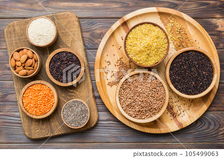 Various superfoods in smal bowl on colored background. Superfood as rice, chia, quinoa, lentils, nuts, sesame seeds, almonds. top view Various superfoods in smal bowl on colored background. Superfood as rice, chia, quinoa, lentils, nuts, sesame seeds, almonds. top view 105499063