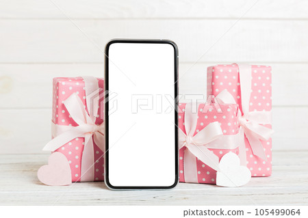mobile phone with blank screen on colored background with hearts, calendar and gift box, valentine day concept perspertive view flat lay mobile phone with blank screen on colored background with hearts, calendar and gift box, valentine day concept perspertive view flat lay 105499064