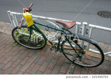 Illegally parked abandoned bicycle with a bicycle parking prohibition card 105499705