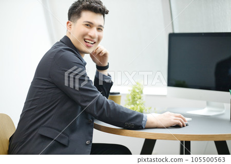 工作在辦公室的一個年輕商人 工作在辦公室的一個年輕商人 105500563