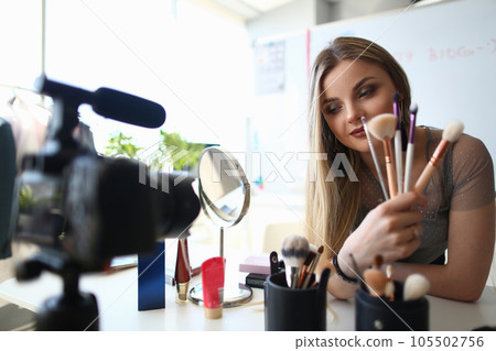 Beauty blogger woman holding product quality review brush recording live video and giving advice to followers Beauty blogger woman holding product quality review brush recording live video and giving advice to followers 105502756