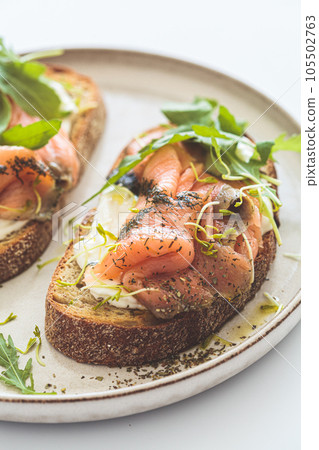 Breakfast toast with cream cheese, salmon, oil and arugula, white background. Keto diet recipe. Breakfast toast with cream cheese, salmon, oil and arugula, white background. Keto diet recipe. 105502763