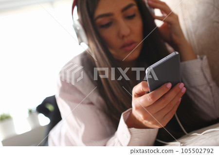 Beautiful young woman listening to music and lying on couch at home 105502792