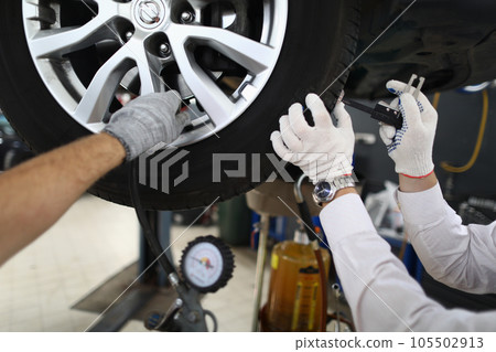 Vehicle inspection Auto technician repairs car tire at service station 105502913