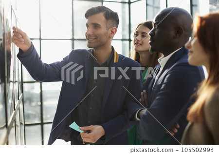 Creative business team looking at sticky notes on glass window 105502993