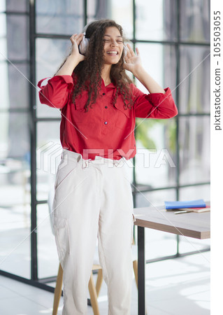 Beautiful smiling young woman in headphones in modern office 105503055