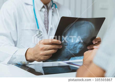 Medical and health care concept. Doctor explaining x-ray results to patient while sitting at the table in office. Medical and health care concept. Doctor explaining x-ray results to patient while sitting at the table in office. 105503867