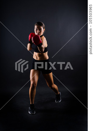 Portrait of a female mixed martial arts fighter with a bandage and gloves on her hands. 105503965