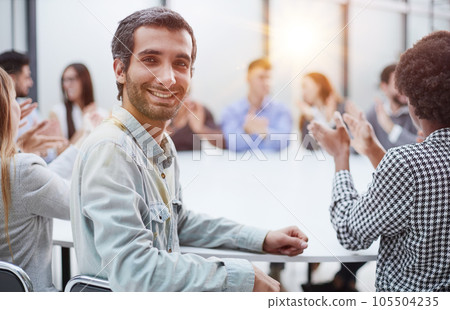 Smiling business group of office workers, executive board members or employees looking at camera sitting at conference table Smiling business group of office workers, executive board members or employees looking at camera sitting at conference table 105504235