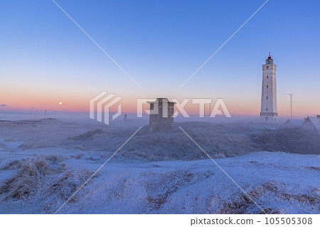Panorama over the dunes and lighthouse of the Danish coastal resort of Blavand at sunrise 105505308