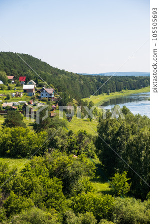 Houses along a beautiful, wide river in the middle of the forest. Calm and quiet place with autumn colors. In the middle of the river island. View from the top to the distance Houses along a beautiful, wide river in the middle of the forest. Calm and quiet place with autumn colors. In the middle of the river island. View from the top to the distance 105505693