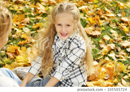 The family has fun in the park. The girl and mother sit on a blanket and rest. The girl looks at the camera and laughs 105505724