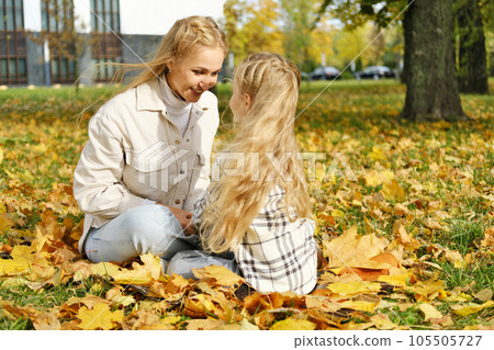 The family has fun in the park. Girl and mother sit on a blanket and relax 105505727