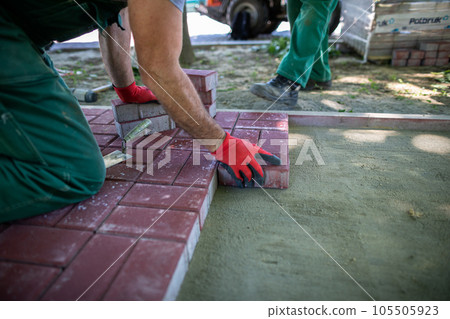 Laying paving stones on a prepared mixture of sand and cement. 105505923