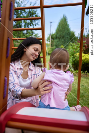 little baby girl with mother on slide in playground little baby girl with mother on slide in playground 105506213