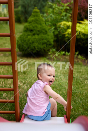 baby girl playing slider in playground in summer baby girl playing slider in playground in summer 105506217