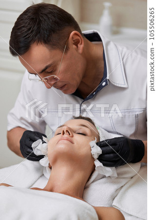beautician cleanses skin of woman with cotton sponge. . 105506265