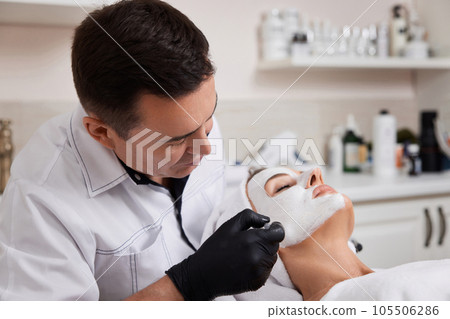 beautician applies the mask to face of woman in the spa salon. skin care beautician applies the mask to face of woman in the spa salon. skin care 105506286