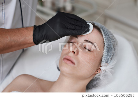beautician cleanses skin of woman with cotton sponge. . beautician cleanses skin of woman with cotton sponge. . 105506295