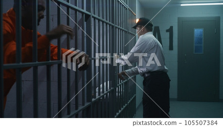 Prison employee brings new prisoner in jail cell Prison employee brings new prisoner in jail cell 105507384