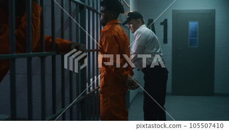 Prison employee brings new prisoner in jail cell 105507410