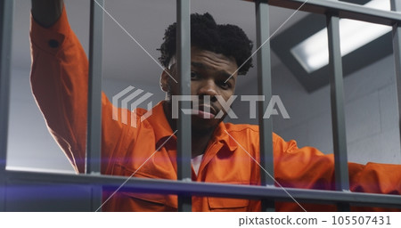 Man leans on prison cell bars and looks at camera Man leans on prison cell bars and looks at camera 105507431