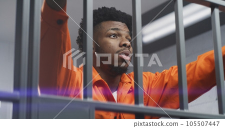 Man leans hands on jail cell bars and kneads neck Man leans hands on jail cell bars and kneads neck 105507447