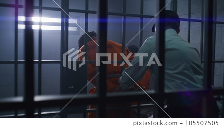 Prison employee leads out inmate of jail cell Prison employee leads out inmate of jail cell 105507505