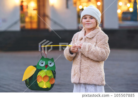 Little preschool kid girl holding selfmade traditional owl lanterns with candle for St. Martin procession. child happy about children and family parade in kindergarten. German tradition Martinsumzug 105507885